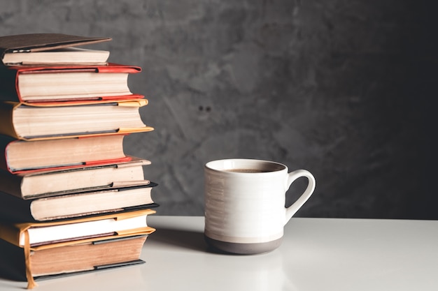 Eine Tasse Kaffee nahe Stapel Bücher auf grauem Hintergrund