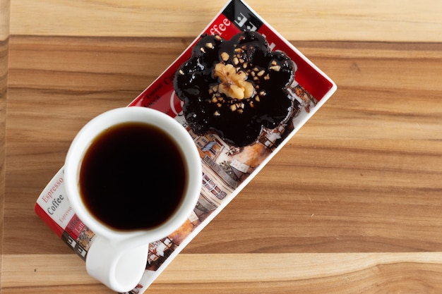 Eine Tasse Kaffee neben einer Praline unter dem Holztisch