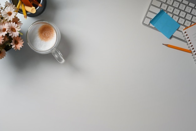 Eine Tasse Kaffee-Stifthalter und eine Tastatur auf einem weißen Schreibtisch