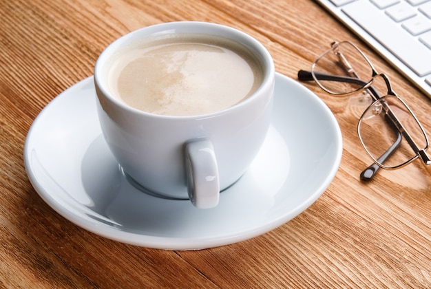 Eine Tasse Kaffee und ein Computer auf dem Tisch. Desktop eines Geschäftsmannes. Zuhause arbeiten.