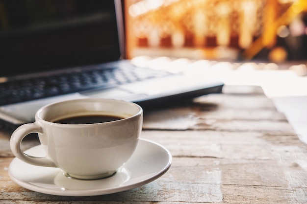 Eine Tasse Kaffee und ein Notebook auf dem Schreibtisch