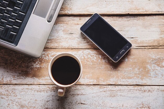 Eine Tasse Kaffee und ein Notebook auf dem Schreibtisch