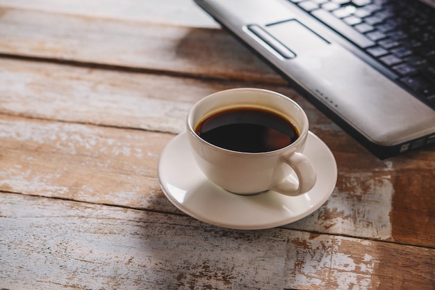 Eine Tasse Kaffee und ein Notebook auf dem Schreibtisch