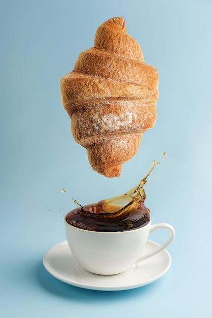 Eine Tasse Kaffee und ein schwebendes Hörnchen auf einer blauen Hintergrundnahaufnahme