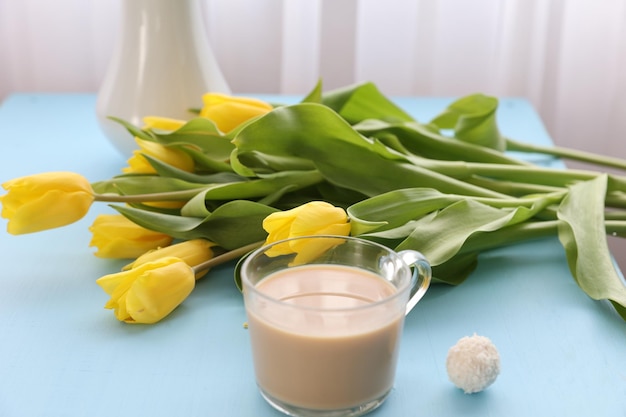 Eine Tasse Kaffee und gelbe Tulpen auf dem Tisch