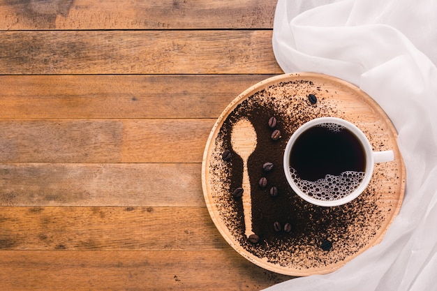 Eine Tasse Kaffee- und Löffelform auf hölzernem Behälter, Draufsicht mit Kopienraum