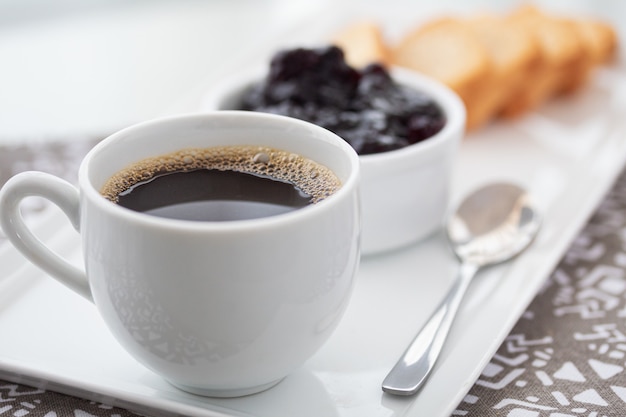 Eine Tasse Kaffee und Toast mit Preiselbeermarmelade auf Weiß.