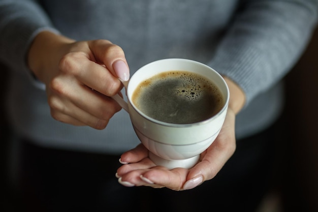 Eine Tasse köstlichen starken Kaffees in weiblichen Händen Konzept trinkt Lifestyle-Arbeitshintergrund