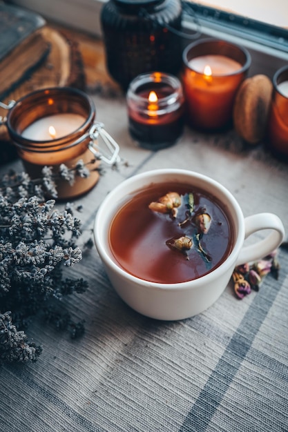 Eine Tasse Kräutertee mit brennenden Kerzen ästhetisch warmes Foto