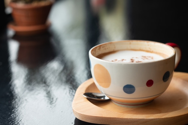 Eine Tasse Latte-Kaffee auf hölzernem Schreibtisch, entspannende Zeit oder die Pause des Kaffees während des Arbeitstages