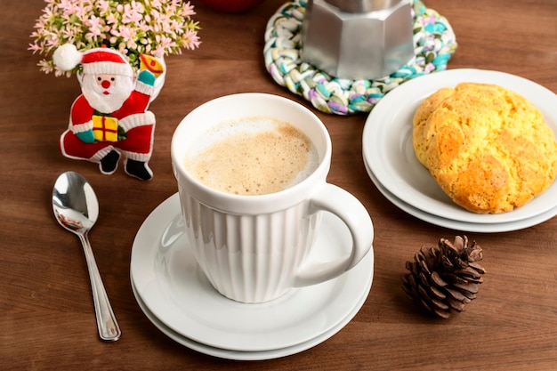 Eine Tasse mit Cappuccino, ein paar Keksen an der Seite und Weihnachtsschmuck, die an die Nähe des Weihnachtstermins erinnern