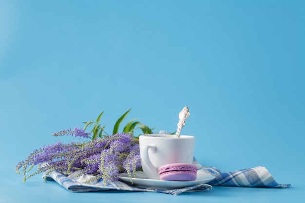 Eine Tasse Morgen Americano-Kaffee mit französischen Macarons auf blauem Hintergrund