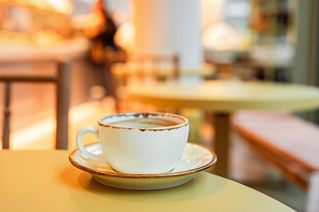 Eine Tasse schwarzes Kaffee auf einer Schüssel am Rand des Tisches in einem Café-Kopierraum