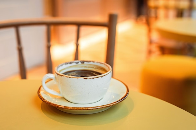 Foto eine tasse schwarzes kaffee auf einer schüssel am rand des tisches in einem café-kopierraum