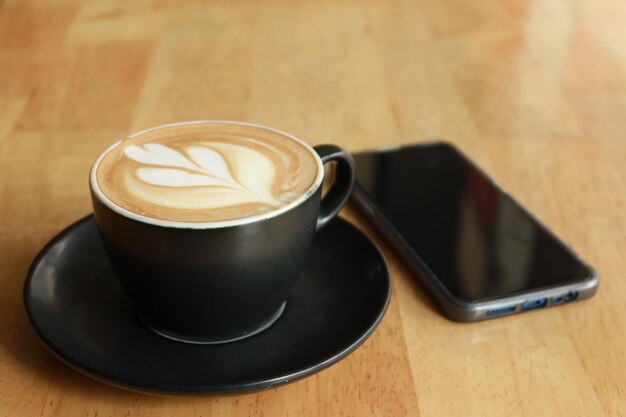 Eine Tasse späten Kaffees mit Blumenformentwurf oben am Café