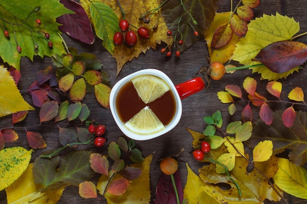 Foto eine tasse tee auf einem hintergrund von mehrfarbigen herbstblättern auf einer holzoberfläche