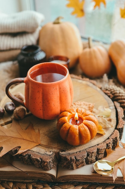 Eine Tasse Tee in Form eines Kürbises vor dem Hintergrund von Stapeln von Pullovern Herbststimmung