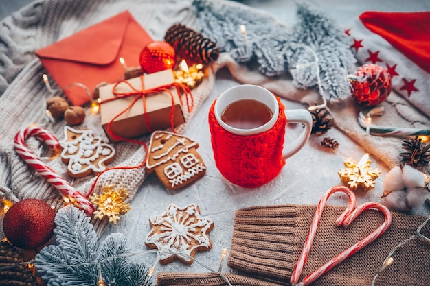 Eine Tasse Tee mit gestrickten roten Lebkuchenkerzen und einer Girlande Weihnachtsatmosphäre zu Hause