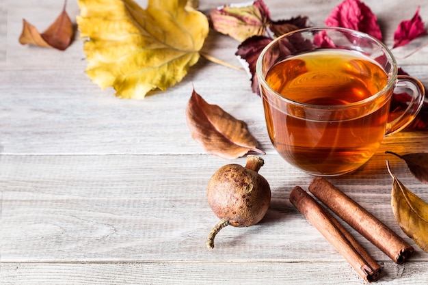 Eine Tasse Tee mit Herbstlaub und Zimtstangen