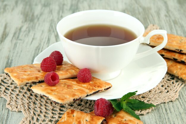 Eine Tasse Tee mit Keksen und Himbeeren auf dem Tisch