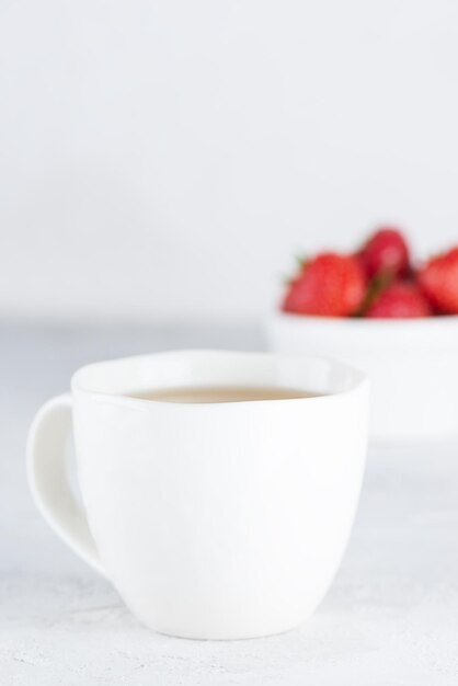 Eine Tasse Tee mit reifen Erdbeeren auf einem hellen Tisch. Selektiver Fokus.