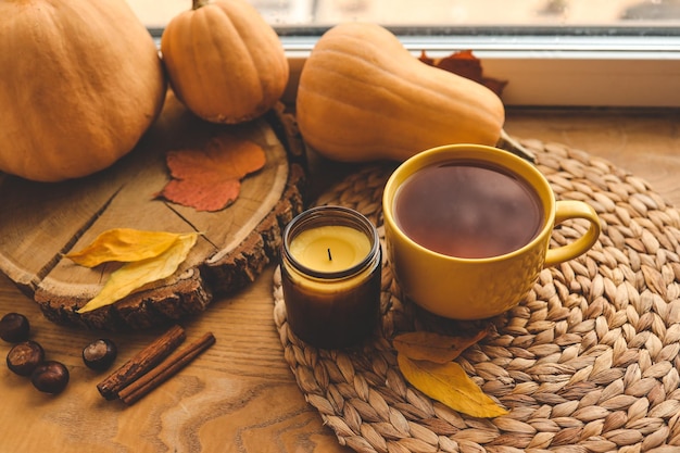 Eine Tasse Tee und eine Kerze am Fenster warmes atmosphärisches Herbstfoto