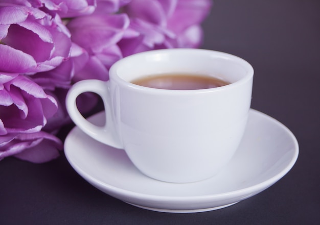 Eine Tasse Tee und violette Tulpen auf dem Tisch