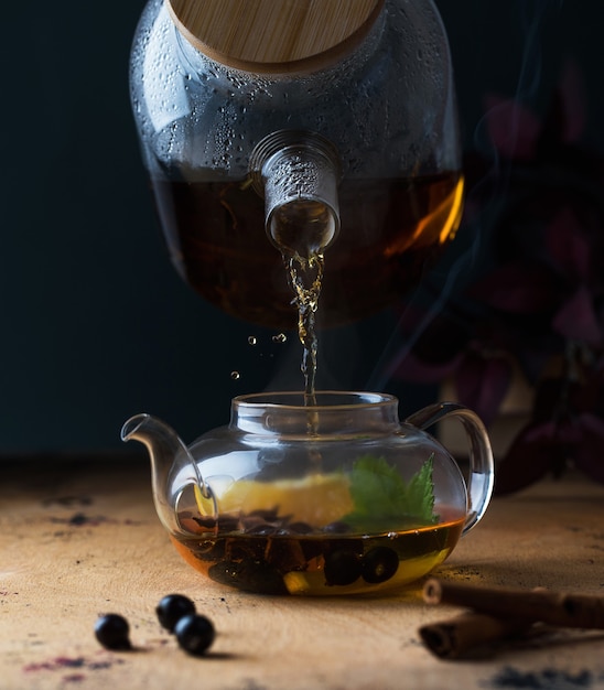 Eine Teekanne mit schwarzem Tee mit Johannisbeeren Zitrone ein Zimtstangen-Herbsthintergrund-Kopierraum