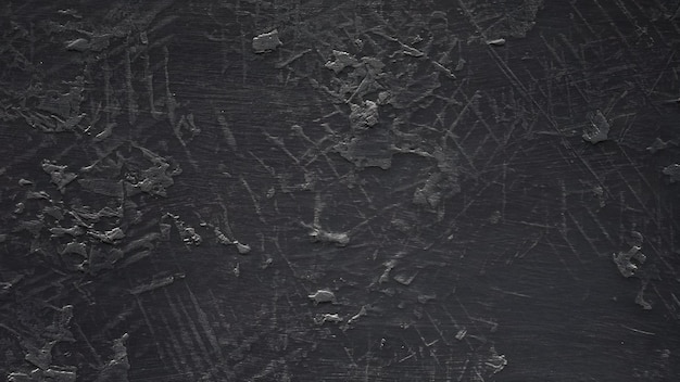 Eine texturierte schwarze Oberfläche mit subtilen Kratzern und Mustern, die durch ein weiches Licht beleuchtet werden