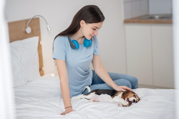 Eine Tierbesitzerin, die auf dem Bett sitzt und glücklich mit ihrem Haustier ist