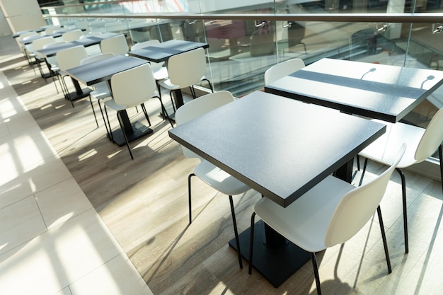 Eine Tischreihe mit weißen Stühlen für Besucher des Food Courts eines modernen Einkaufszentrums.