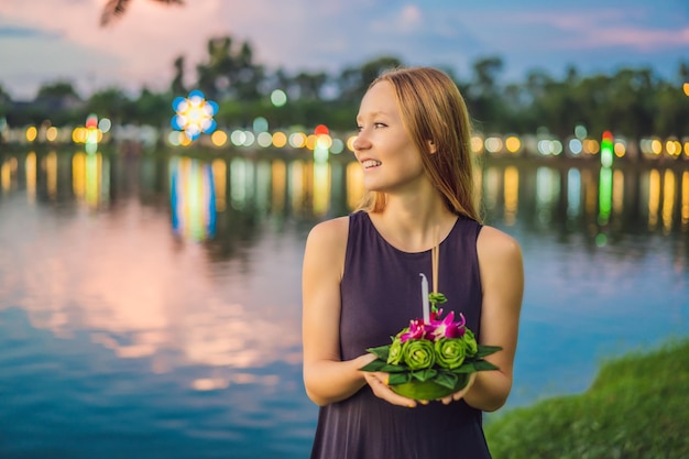 Eine Touristin hält den Loy Krathong in ihren Händen und will ihn gerade ins Wasser werfen