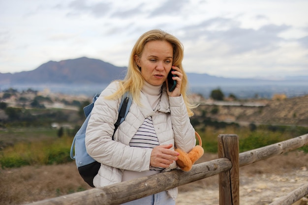 Eine Touristin kommuniziert auf einem Mobiltelefon vor dem Hintergrund der Natur