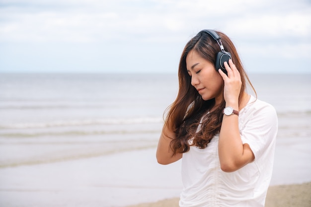 Eine traurige Frau, die Musik mit Kopfhörer am Meer hört