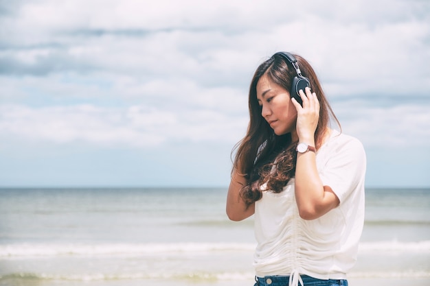 Eine traurige Frau, die Musik mit Kopfhörer am Meer hört