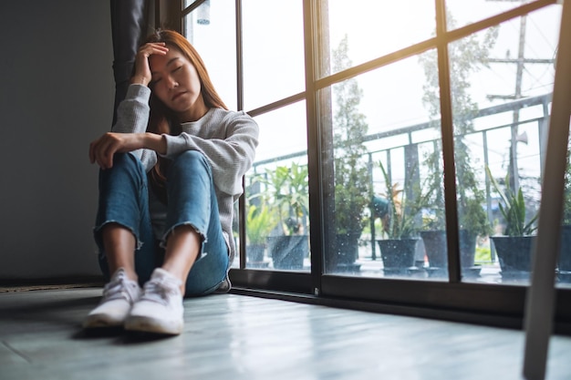 Foto eine traurige und gestresste junge asiatin, die allein im zimmer sitzt