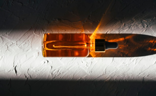 Eine Tropfflasche aus klarem Glas mit Serum, Öl und Hyaluronsäure, ein Holzschnitt im Sonnenlicht.