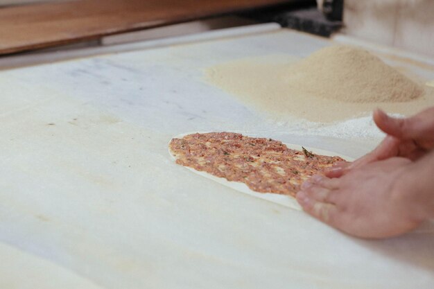 Eine türkische Pizza oder Lahmacun Fast Food und beliebtes Street Food in Mittelmeerländern zubereiten D