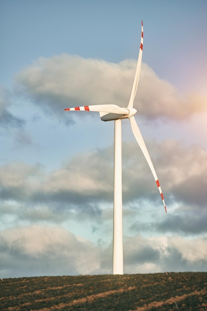 Eine Turbinenmühle Windkraftanlage im grünen Feld gegen den blauen Himmel mit flauschigen Wolken Konzept der grünen Energie und der nachhaltigen Zukunft