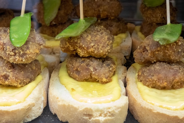 Eine typische Tapa oder ein Aperitif, serviert in einer spanischen Bar, zwei Fleischbällchen mit Paprika auf Brot mit Käse