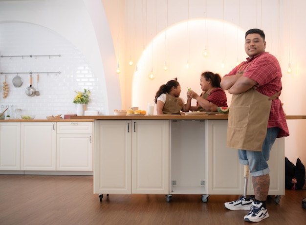 Eine übergroße Familie mit einem Vater, der ein Beinprothese trägt, essen zusammen, nachdem sie gekocht haben.