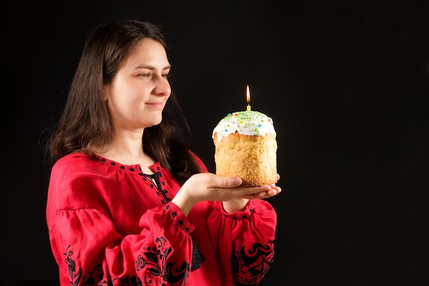 Eine ukrainische Frau in bestickter Nationaltracht hält einen Osterkuchen