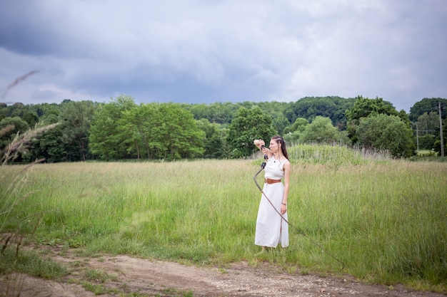 Eine Ungarin steht auf dem Feld in einem Leinenkleid mit einer Peitsche