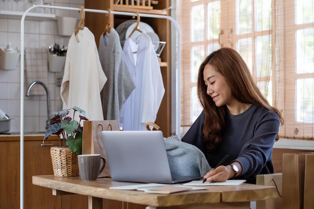 Eine Unternehmerin, die Kleidung verkauft und Bestellungen von Kunden für das Online-Shopping-Konzept überprüft