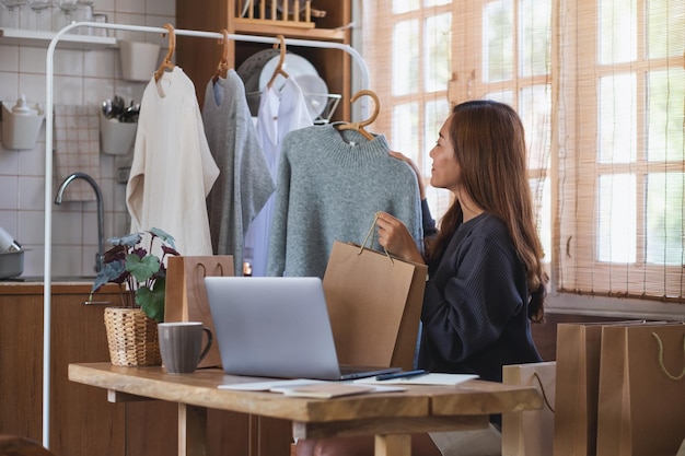 Eine Unternehmerin, die zu Hause einen Laptop benutzt, um Kleidung online zu verkaufen oder Produkte in sozialen Medien zu bewerten