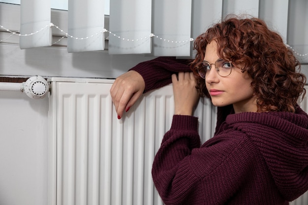 Foto eine unzufriedene frau sitzt an der heizung, weil es im haus keine heizung gibt