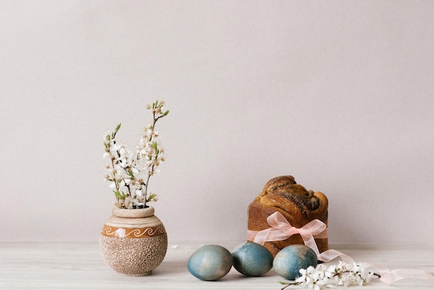 Eine Vase mit Apfelblumen und ein mit Eiern bemalter Osterkuchen auf dem Tisch