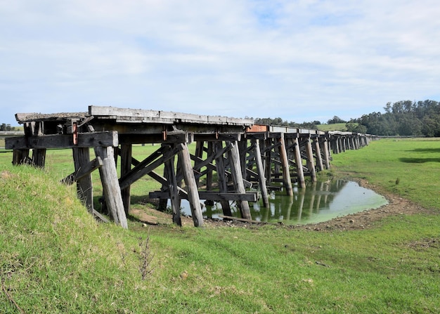 Eine verlassene Holzbrücke über ein grasbewachsenes Feld gegen den Himmel