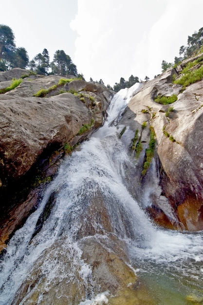 Eine vertikale Aufnahme eines Wasserfalls durch eine bergige Landschaft