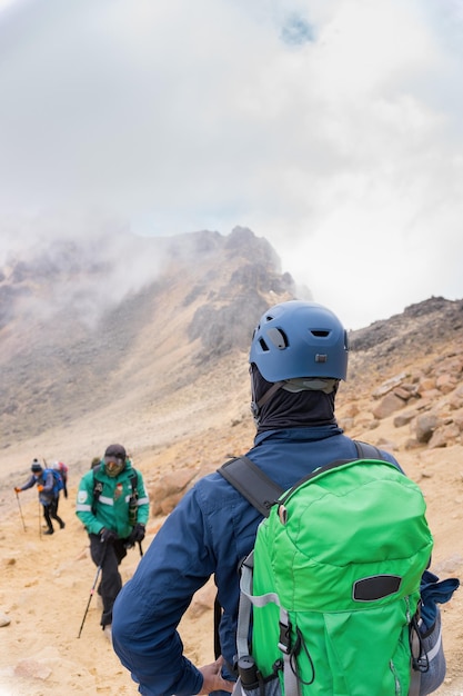 Eine vertikale Aufnahme von Wanderern mit Rucksäcken, die an einem nebligen Tag den Vulkan Iztaccihuatl erklimmen